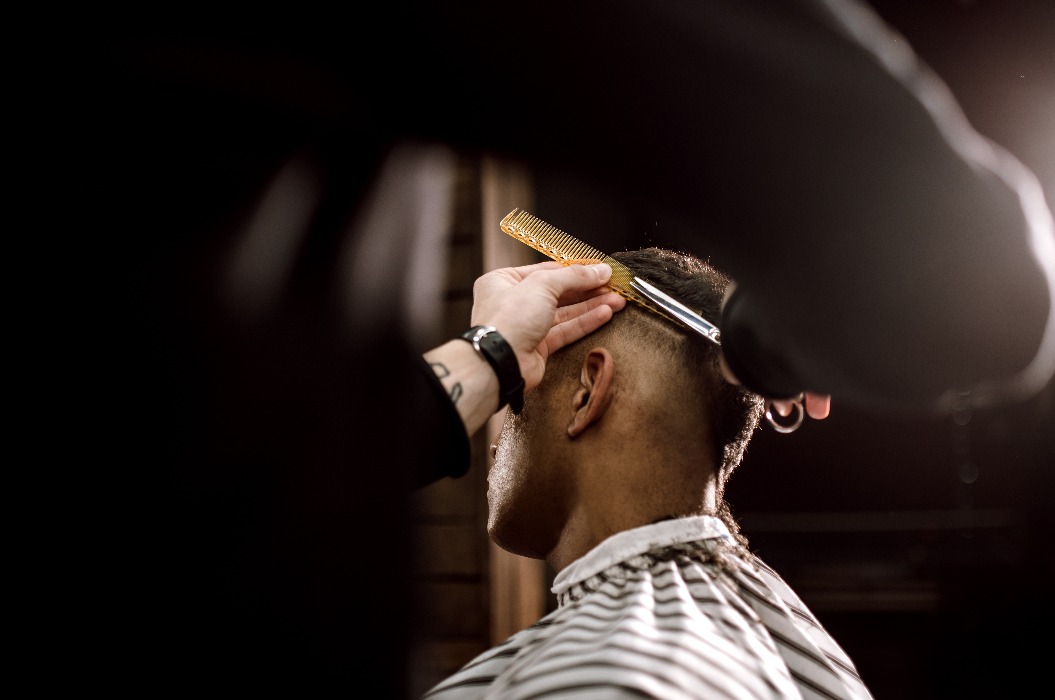 Der Barbier schert die Haare an den Seiten für einen stilvollen schwarzhaarigen Mann im Barbershop. Mode und Stil für Männer